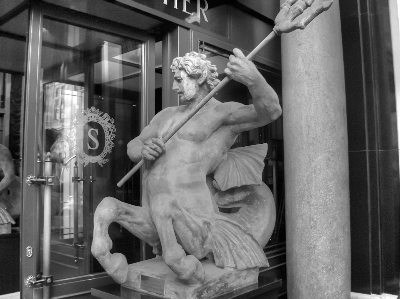 A cropped, grayscale edit of a photo of an ichthyocentaur outside of Hotel Sacher in Vienna.